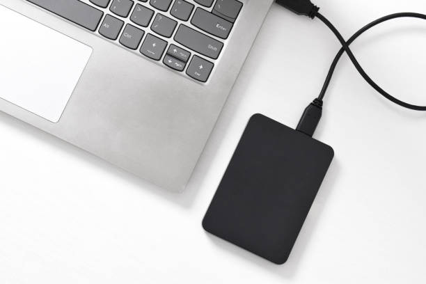 istock External backup hard disk drive connected to laptop on white background 2153404959