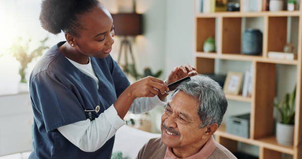living room, elderly man and nurse with comb for hair care, grooming or support in nursing home. senior person, medical professional and discussion with helping for wellness, hairstyle and retirement - cuidado com o corpo imagens e fotografias de stock