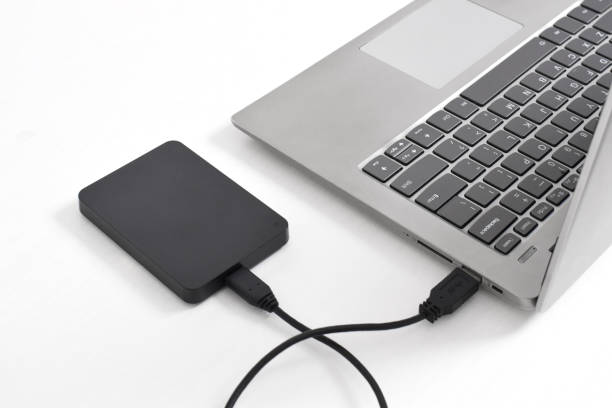 istock External backup hard disk drive connected to laptop on white background 2153405505