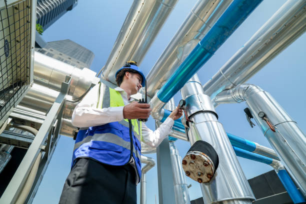 istock Industrial engineer adjusting pipeline valve with radio communication on construction site. Engineer on urban construction site using radio to coordinate with team on a sunny industrial rooftop. 2153406263