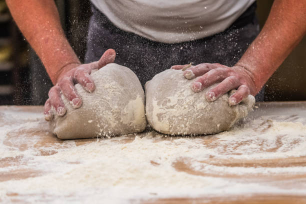 istock A baker kneads bread dough in the bakery. Vintage style with grain. Vertical. 2153406340