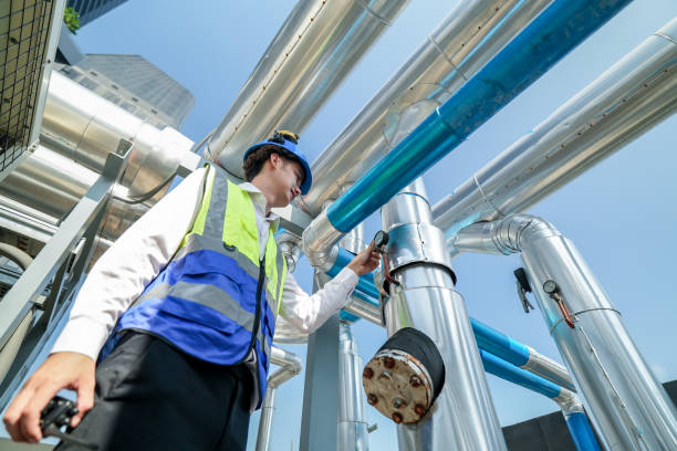 istock Industrial engineer adjusting pipeline valve with radio communication on construction site. Engineer on urban construction site using radio to coordinate with team on a sunny industrial rooftop. 2153407510