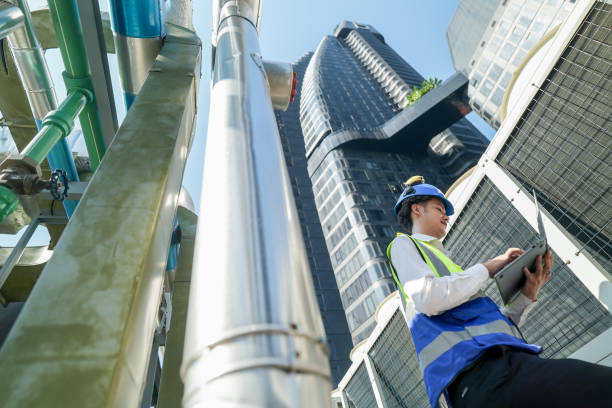 istock Industrial engineer adjusting pipeline valve with radio communication on construction site. Engineer on urban construction site using radio to coordinate with team on a sunny industrial rooftop. 2153408088