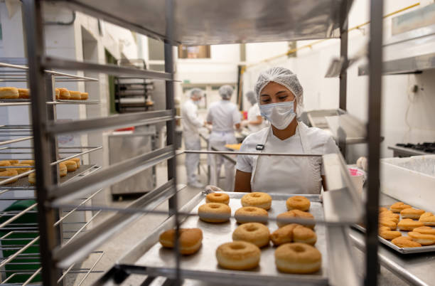 istock Woman working at an industrial bakery making donuts 2153409176