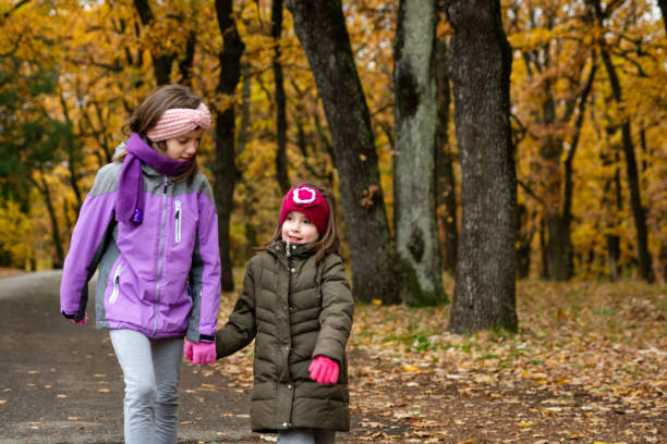 istock Two girls holding hands in autumn park 2153410521