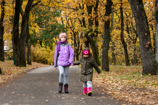 Full length of two sisters walking in autumn park