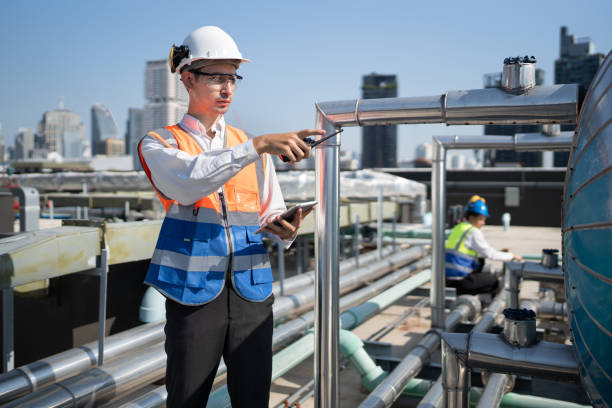 istock Portrait Asia male engineer in protective workwear is performing a conducts system check with use tablet computer at rooftop building 2153414349