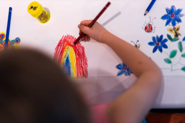 Close-up of child dipping brush into bottle of paint