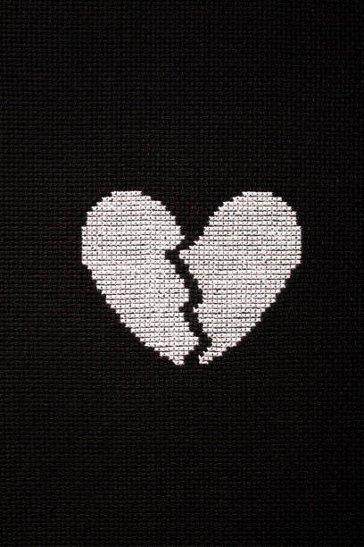 istock Broken heart is embroidered with white threads on black fabric. 2153418077