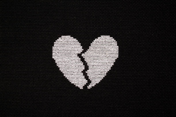 istock Broken heart is embroidered with white threads on black fabric. 2153418090