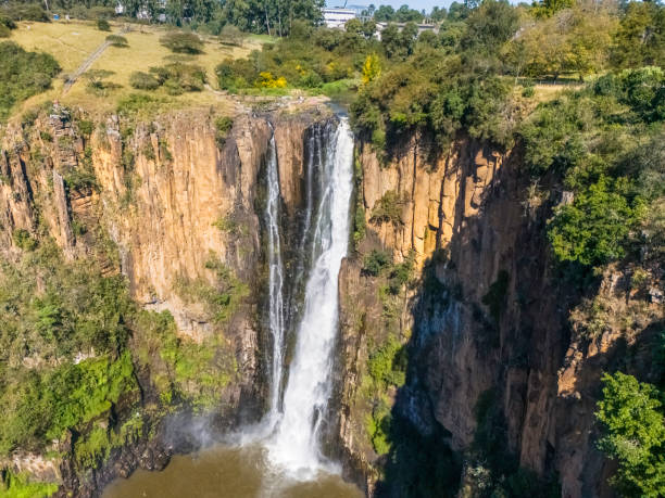 Howick Falls in Kwazulu Natal, it is approximately 95m in height (310 feet) and lies on the Umgeni River, people seen above doing washing and bathing.