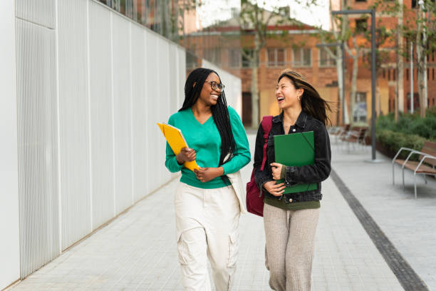 istock Two happy students girls talking and walking in University campus after classes 2153425198
