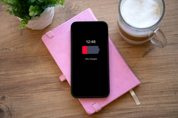 istock phone with low charged battery on screen background pink notepad 2153426455