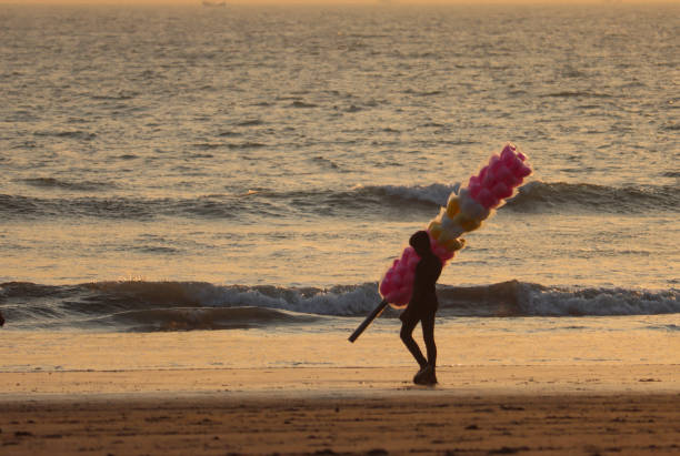 A cotton candy hawker walking on the beach at sunset in Cox's Bazar, Bangladesh