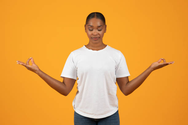 istock African american millennial lady meditating making om gesture, orange background 2153440797