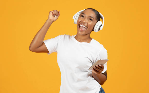 istock black woman in wireless headset with smartphone enjoys tunes, studio 2153440810