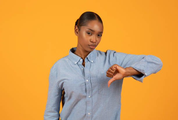 istock Young black woman expresses discontent giving thumbs down in studio 2153440828