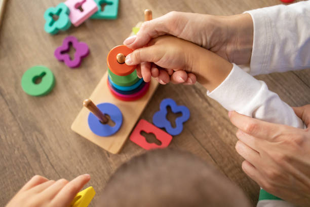 Exploring Sensory Toys with Nurse A dedicated female nurse supports a young autistic boy using sensory toys to enhance motor abilities. child playing with toys stock pictures, royalty-free photos & images