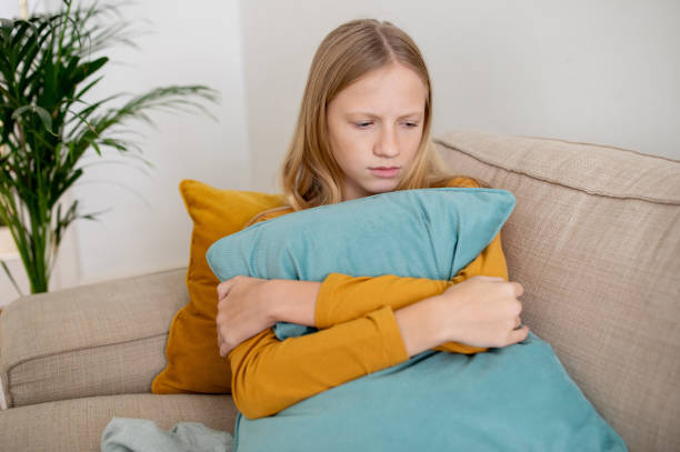 Young Girl Looking Downcast While Hugging Pillow on Couch