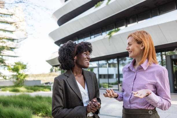 istock Two business women standing outside modern office building and talking 2153447551