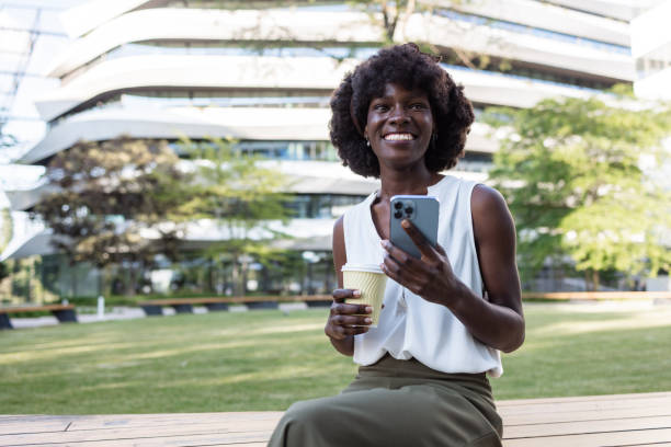 istock Woman enjoying coffee and using smartphone outdoors in the park 2153447637
