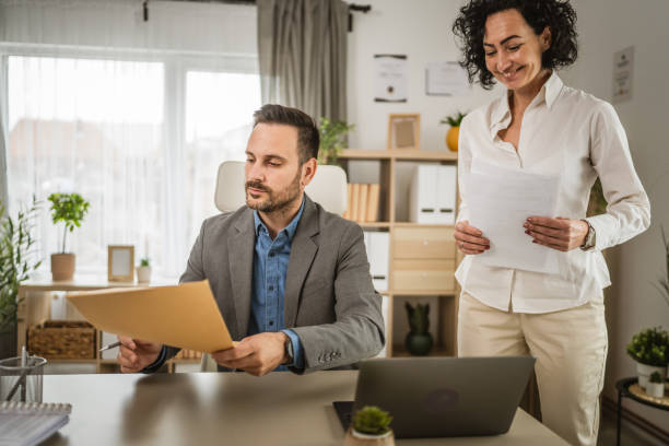 istock Two colleagues man and woman hold documents and work together at office 2153450243