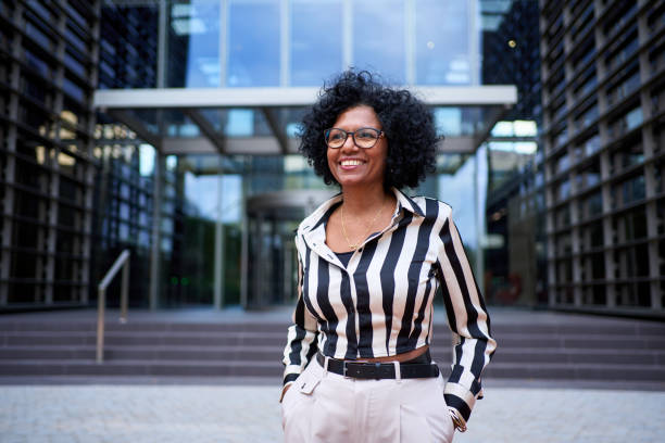 retrato da mulher de negócios de cabelo cacheado afro-americano alegre posando para foto em pé - autoridade - fotografias e filmes do acervo