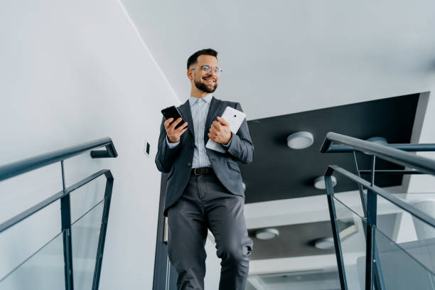 istock Businessman on stairs using two phones 2153458221