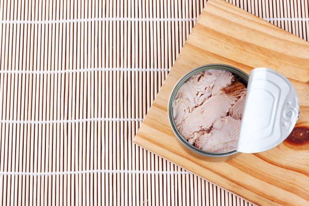 istock open canned tuna can on wooden cutting board top view 2153459125
