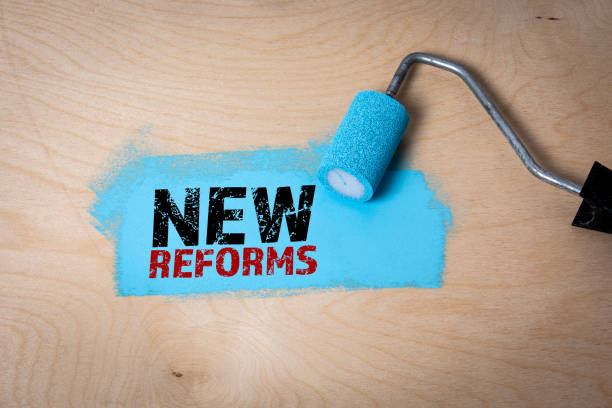 istock NEW REFORMS. Blue paint and paint roller on a plywood background 2153462176
