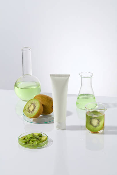 istock Kiwi composition cosmetic science research template for advertising, several laboratory instruments and blank label tube placed on white table over white background. Copy space, front view 2153465452