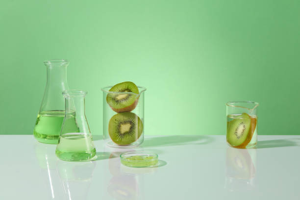istock Pastel green background against some lab instruments placed on white table, vacant space in the center for showing products manufactured from kiwi ingredients. Front view photo, space for advertising 2153468261