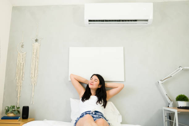 istock Content woman relaxes on a bed in a cool room with a mini split air conditioning unit during a hot summer day 2153468371