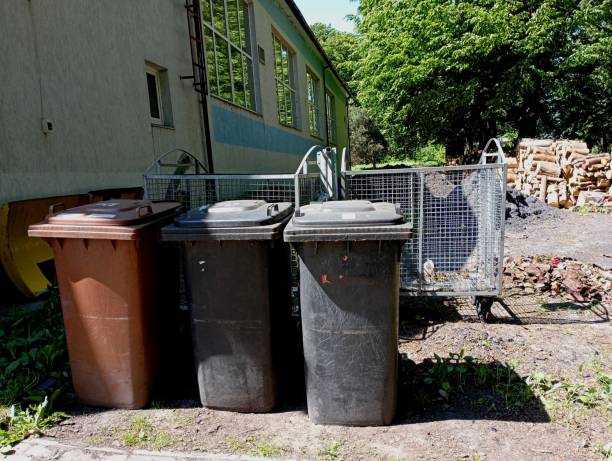 istock Three plastic garbage containers near the house next to large metal containers. The topic of cleaning and garbage removal in the city. 2153472690