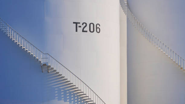 istock Spiral staircases on 2 white storage fuel tanks with sunlight and shadow on surface 2153479043
