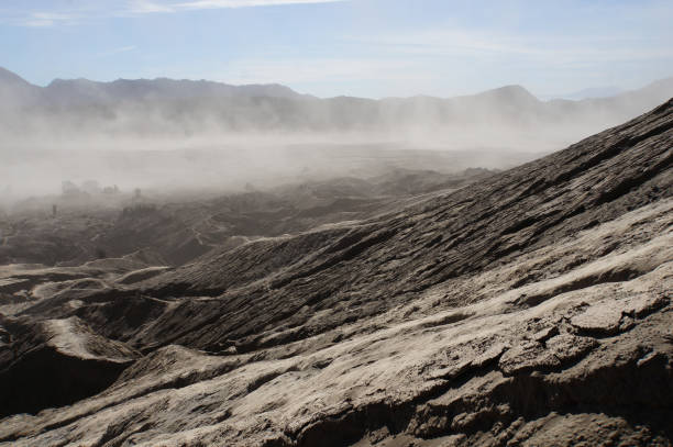 The rough surface, with layers of rocks piled on top of each other far into the distance. Covered by a sandstorm around the mountain Bromo, Indonesia