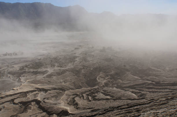 The rough surface, with layers of rocks piled on top of each other far into the distance. Covered by a sandstorm around the mountain Bromo, Indonesia