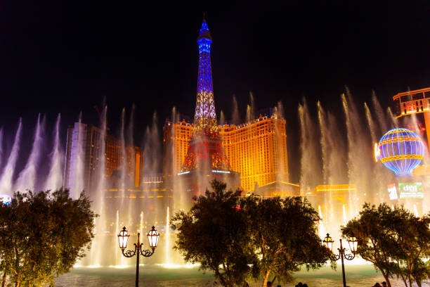 Las Vegas, Nevada, USA - June 18, 2023 : Bellagio Fountain water show at night with the illuminated Eiffel Tower of Paris Las Vegas Hotel and Casino in the background.