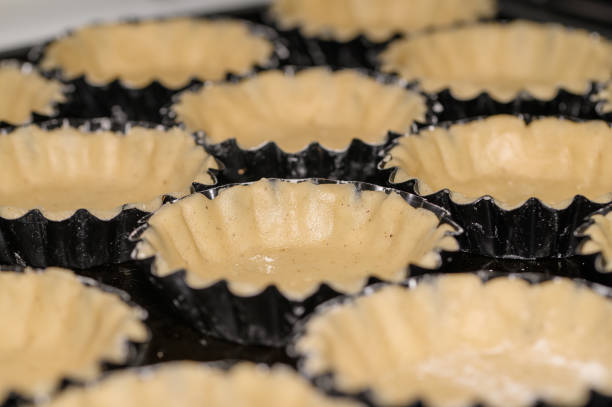 Raw shortcrust pastry dough in metal molds before baking