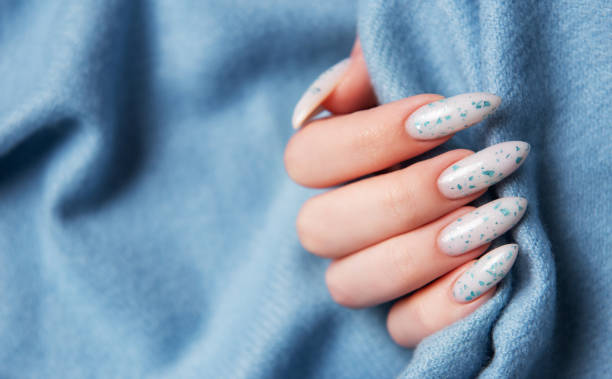 istock Female hands with blue nail design on blue textile background. 2153490003