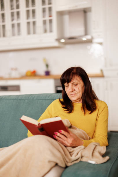 istock Senior woman reading a book at home 2153492288