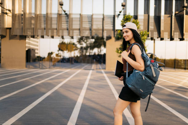 istock Smiling young woman looking away while walking outdoors at university campus 2153499571