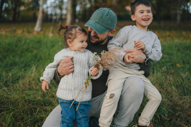 istock Father holding children close while telling them something while in the autumn park for a walk. 2153502853