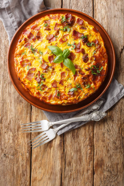 istock Delicious breakfast omelette with chicken, cheese, bacon and herbs close-up in a plate. Vertical top view 2153508549