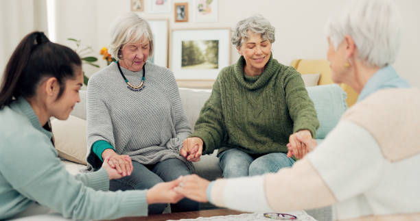 istock Senior group, holding hands and pray in elderly care for support, trust or unity in social gathering at home. Mature women touching in team activity, share or praying for hope in retirement together 2153510255