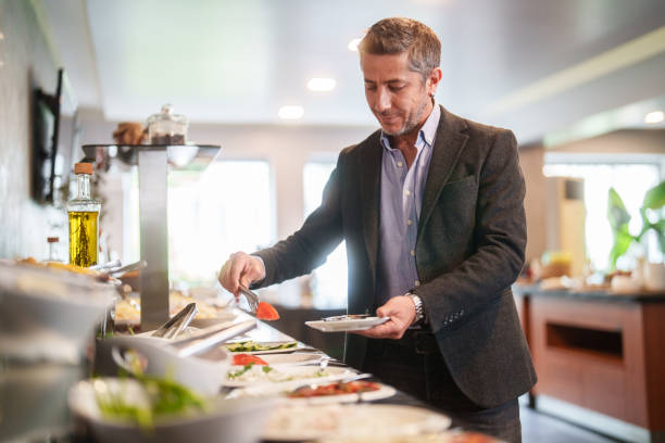 Businessman in self service breakfast room in hotel, preparing a plate.