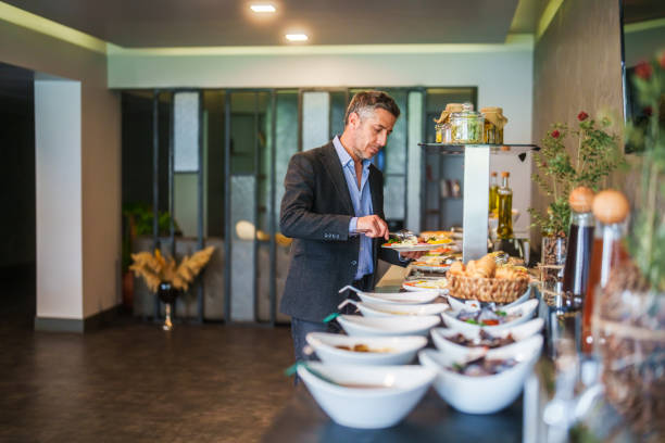 istock Businessman in self service breakfast room in hotel, preparing a plate. 2153516928