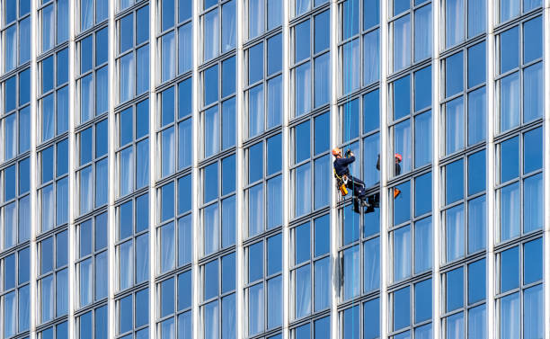 Milano, Italy August, 9 2024: Industrial climbers hanging on the rope while cleaning the walls of a skyscraper