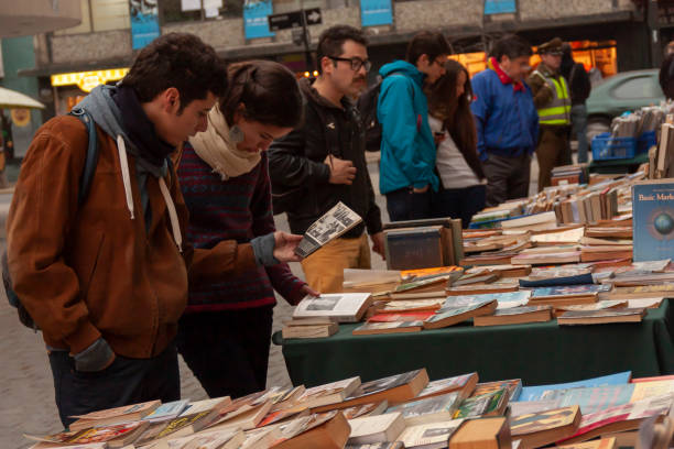Santiago, Chile - May 14, 2017: People enjoying a street market checking a book in a bookstand in Lastarria neighborhood in autumn season.