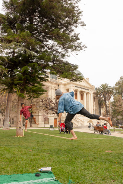 Santiago, Chile - May 15, 2017: A group of people enjoying a cloudy autumn day in front of the Bellas Artes Museum / Fine Arts Museum doing slackline walking over a rope.